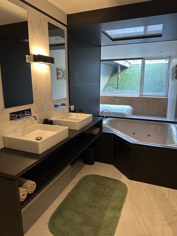 Badkamer met dubbele wastafel, spiegelwand en whirlpoolbad