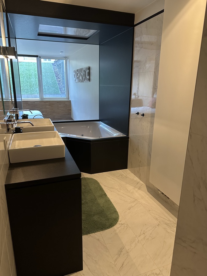 Badkamer met whirlpoolbad, wastafel en marmeren vloer
