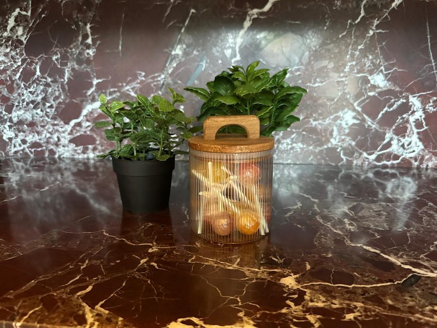 Glazen voorraadpot met lolly's en plantjes op het rode marmeren werkblad