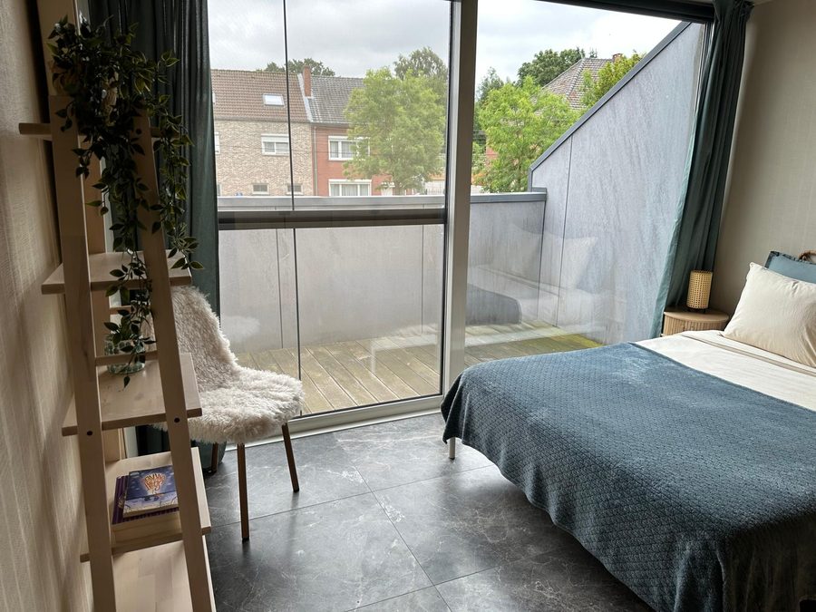 Slaapkamer met schuifraam op het terras, ladderrek en stoel met schapenvacht
