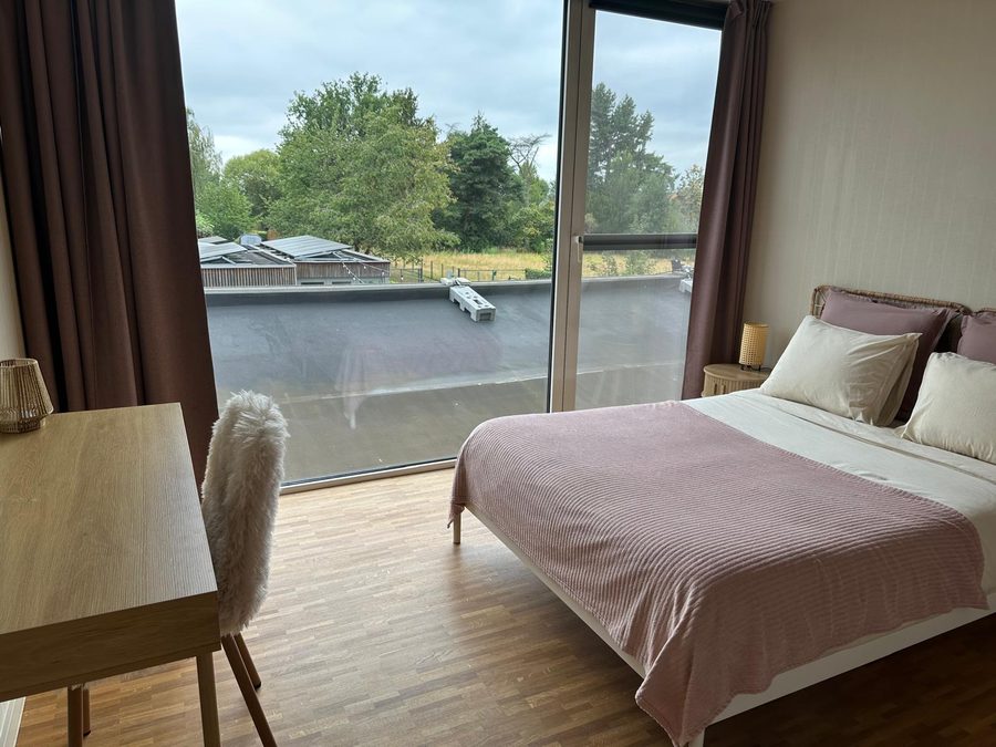 Slaapkamer met bureau, stoel met schapenvacht en schuifraam op het dakterras