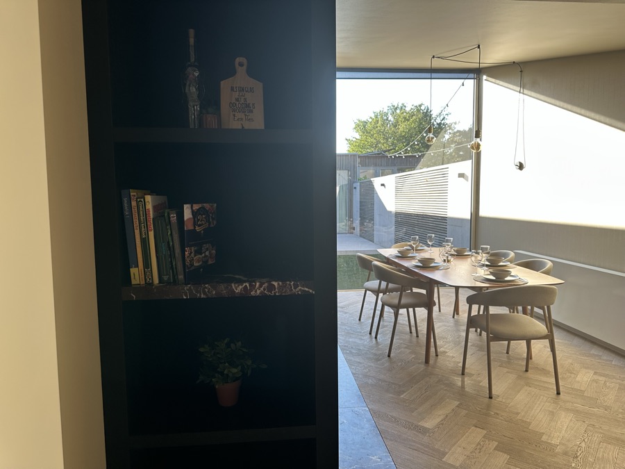 Zwarte boekenkast met doorkijk naar de eettafel en het terras