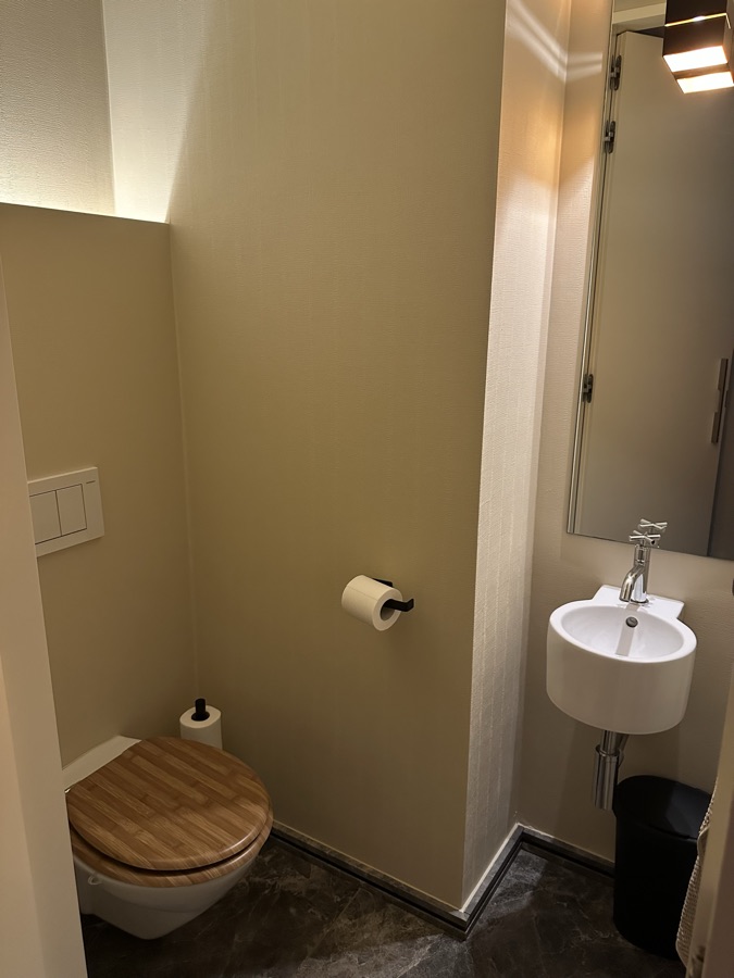 Apart toilet met houten bril en handwasbakje